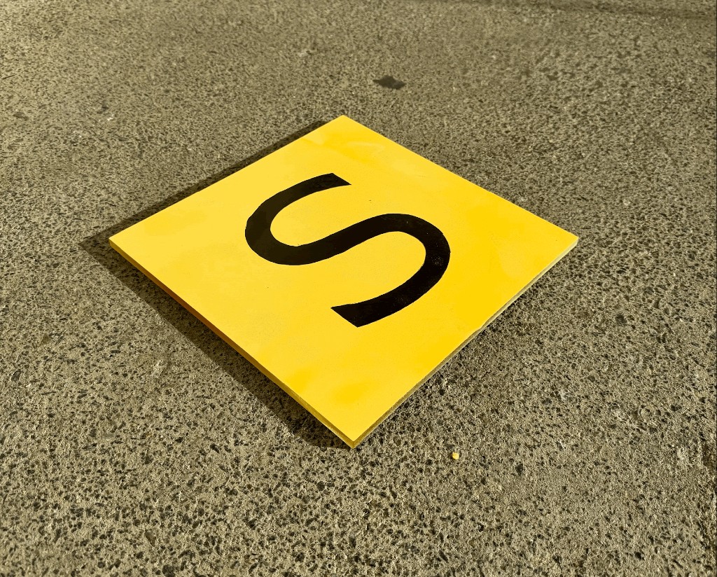 SpotSwitch — yellow S plate prototype on concrete